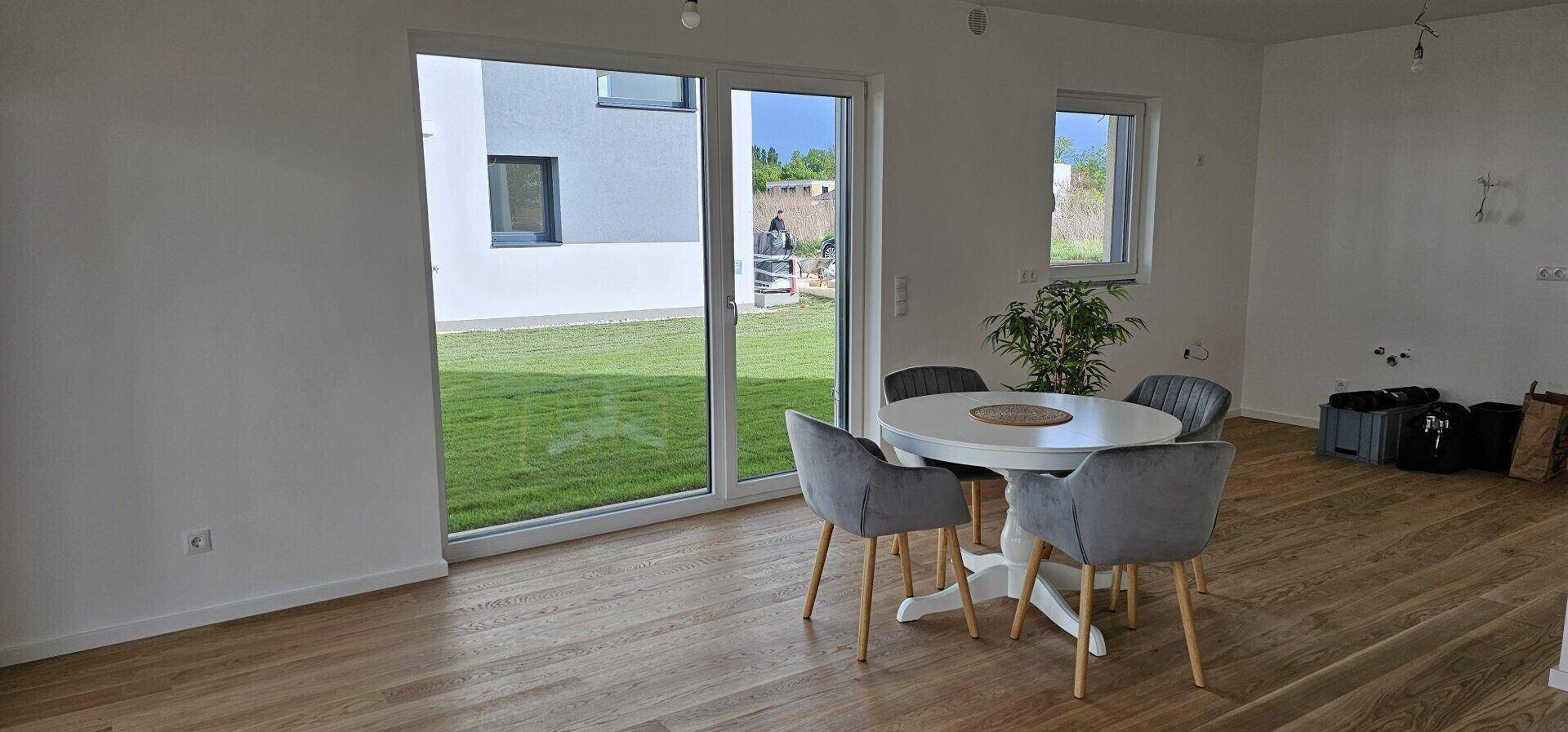 Heller Essbereich mit Holzboden und großzügigen Fenstern, die viel Tageslicht hereinlassen.