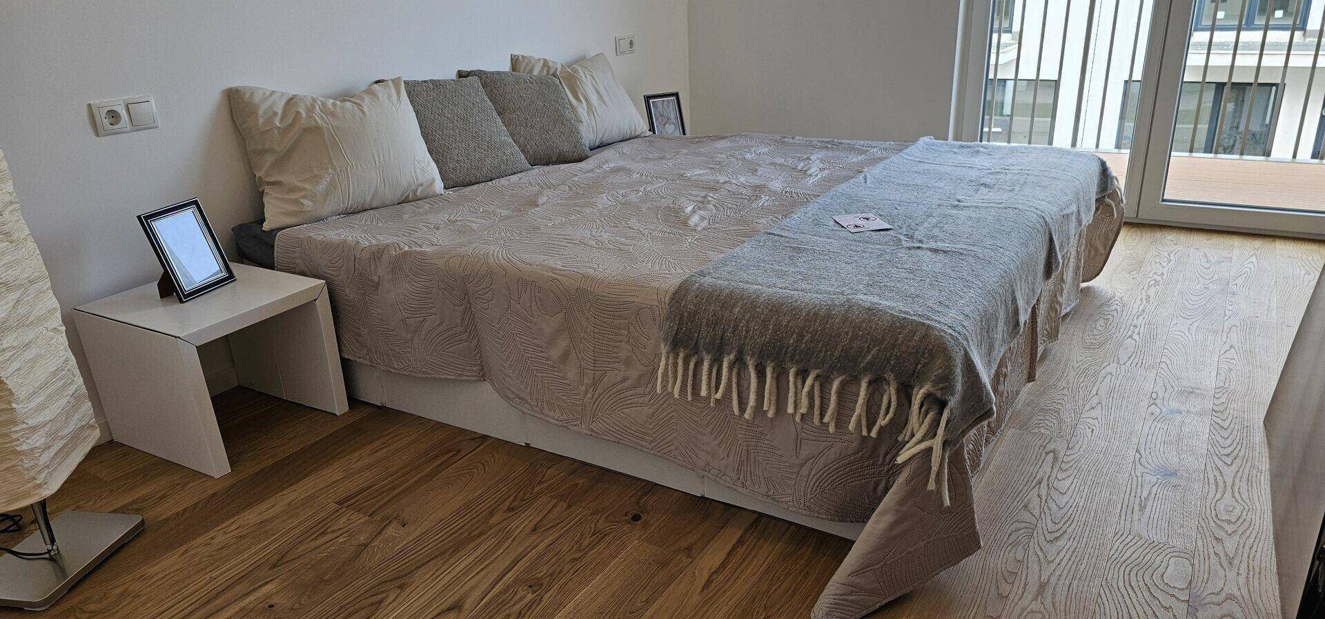 Gemütliches Schlafzimmer mit Doppelbett, Holzboden und Zugang zu einem Balkon.