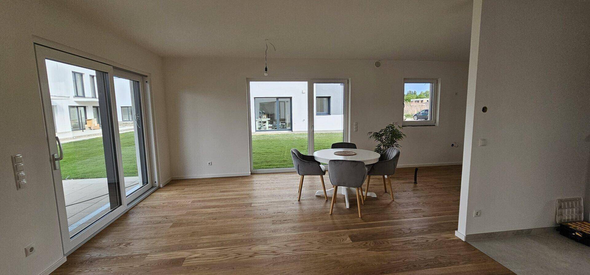 Geräumiger Essbereich mit Holzboden und großen Schiebetüren, die zum Garten führen.