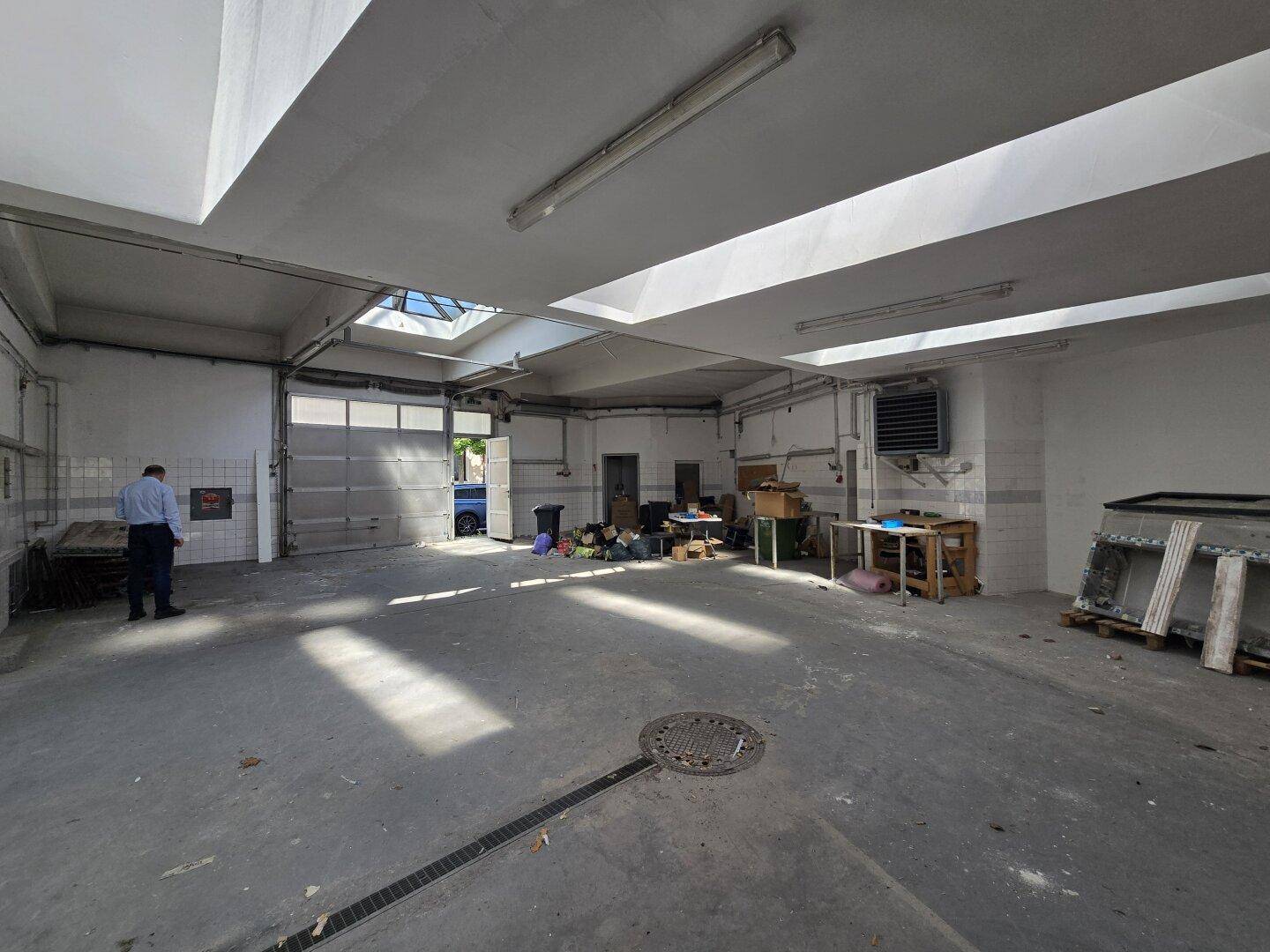 Große Garagenhalle mit Rolltor, Betonboden und viel Platz, geeignet für Fahrzeuge oder Lagerung.