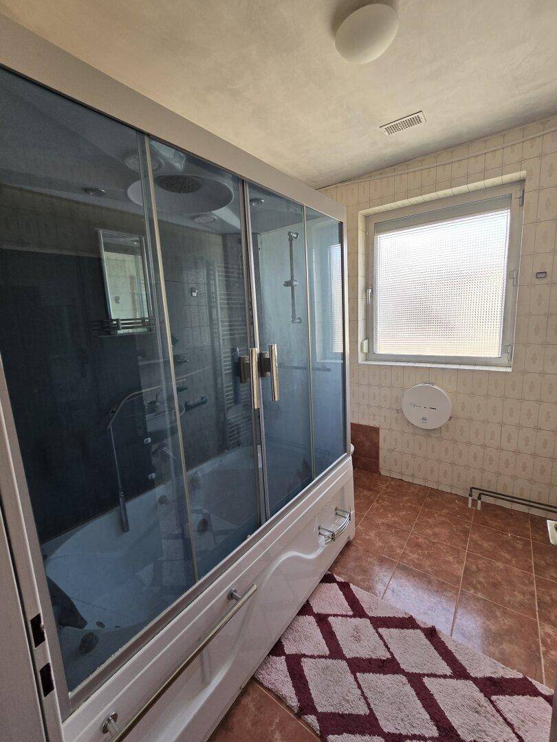 Badezimmer mit kombinierter Dusch-Badewanne, gefliesten Wänden und Fenster.