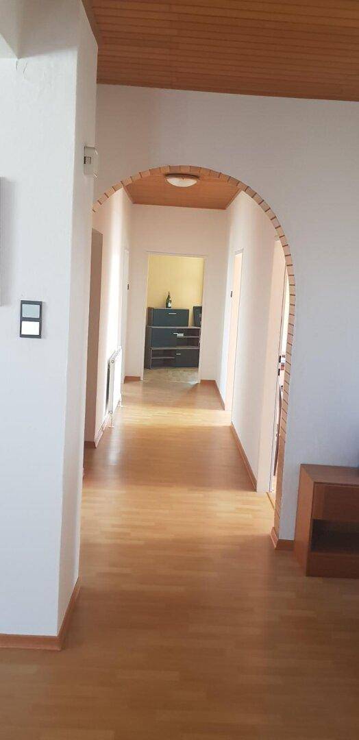 Langer Flur mit Rundbogen, Holzdecke und Laminatboden, der zu weiteren Räumen führt.