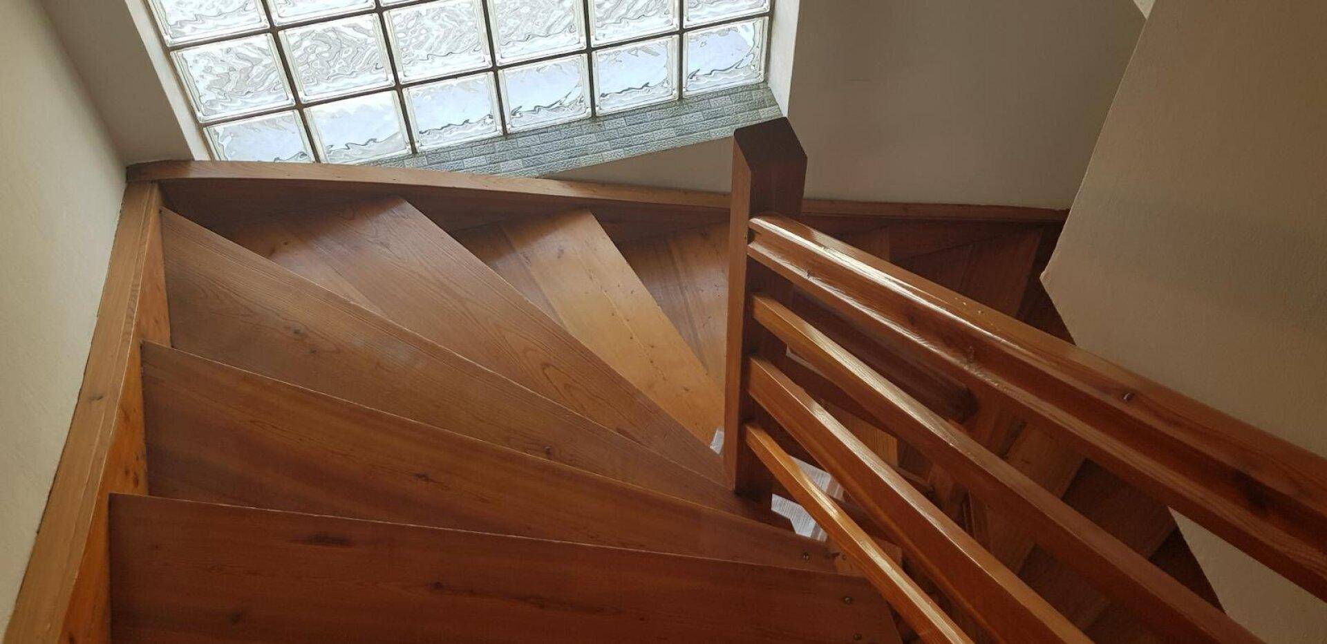 Holztreppe mit einem Glasbausteinfenster darüber, das für natürliches Licht sorgt.