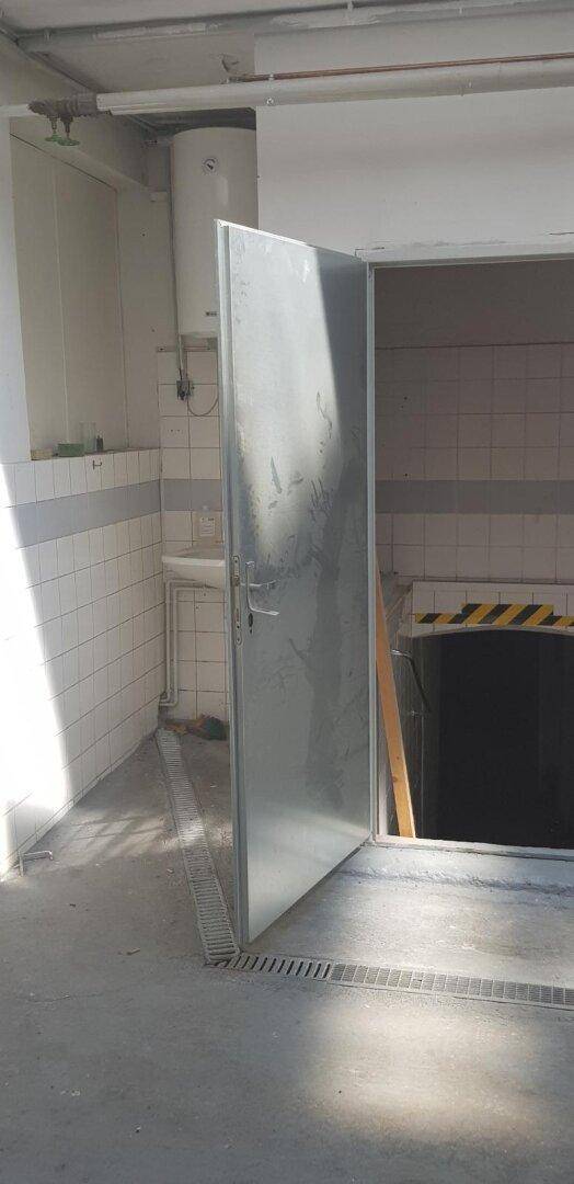 Innenraum mit Boiler, gefliesten Wänden und Abflussrinne, möglicherweise ein Hauswirtschaftsraum.