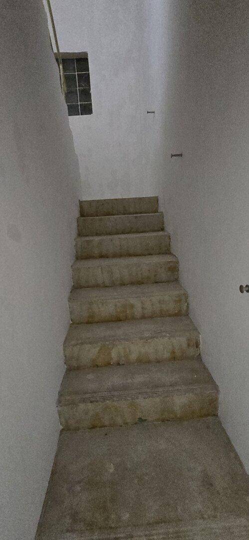 Treppenhaus mit Betonstufen und einem kleinen Fenster, das spärliches Licht spendet.