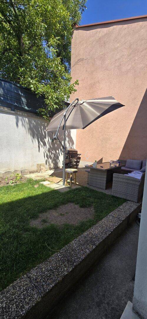 Gemütlicher Gartenbereich mit Sonnenschirm, Sitzgelegenheiten und Rasenfläche.