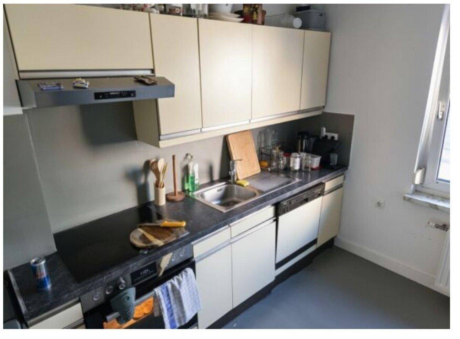 Funktionale Küche mit beigen Schränken, dunkler Arbeitsplatte und integrierten Geräten.