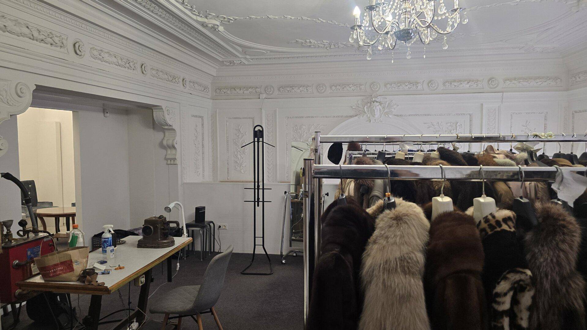 Geräumige obere Etage mit Kleiderständern, Nähbereich und kunstvoller Stuckdecke.