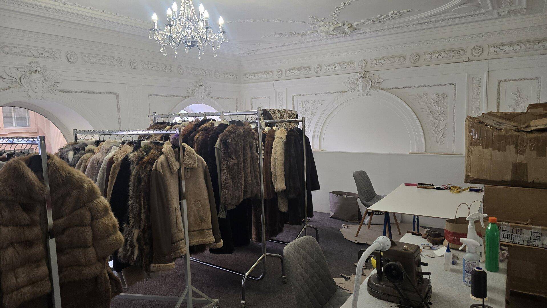 Obere Etage mit Kleiderständern, Nähmaschine und prächtiger Stuckdecke, bereit für Anpassungen.