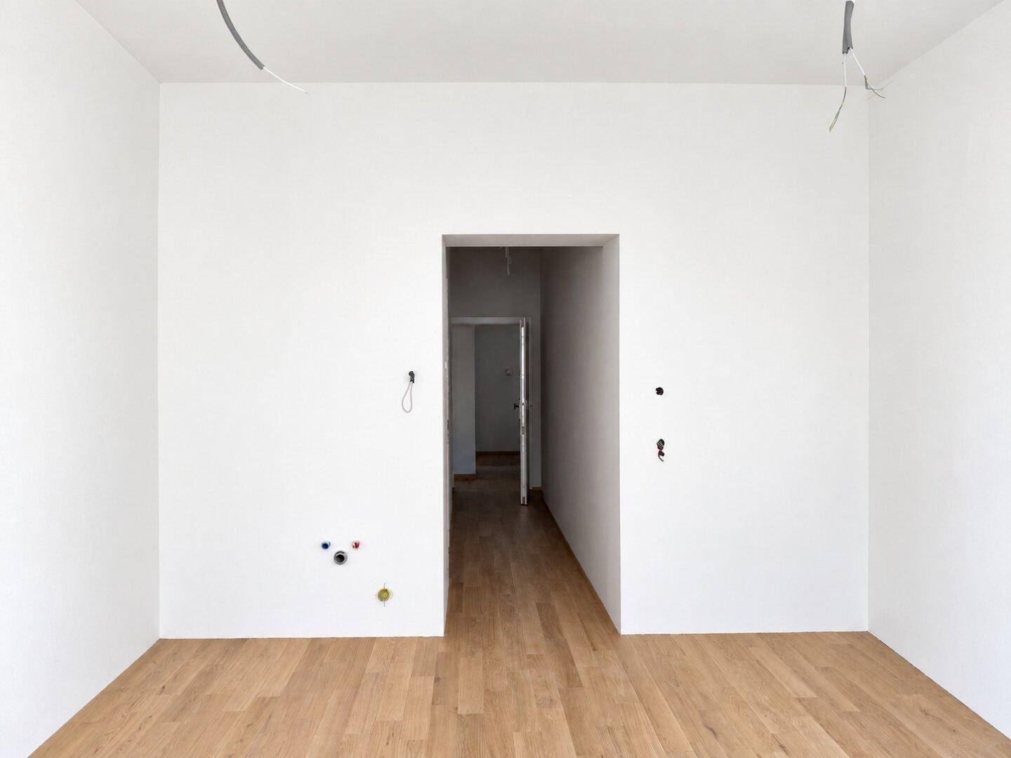 Unmöblierter Raum im Neubau mit hellen Wänden und Holzboden, bereit für den Ausbau.