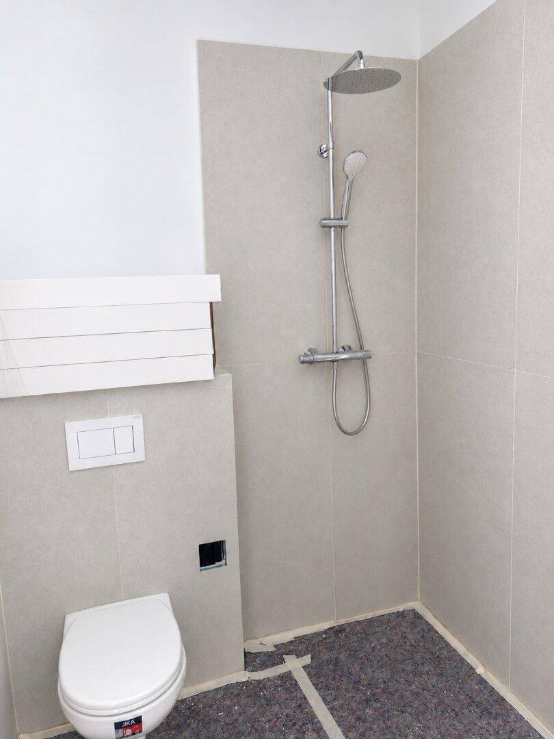 Modernes Badezimmer mit bodengleicher Dusche, Regendusche und wandhängender Toilette.