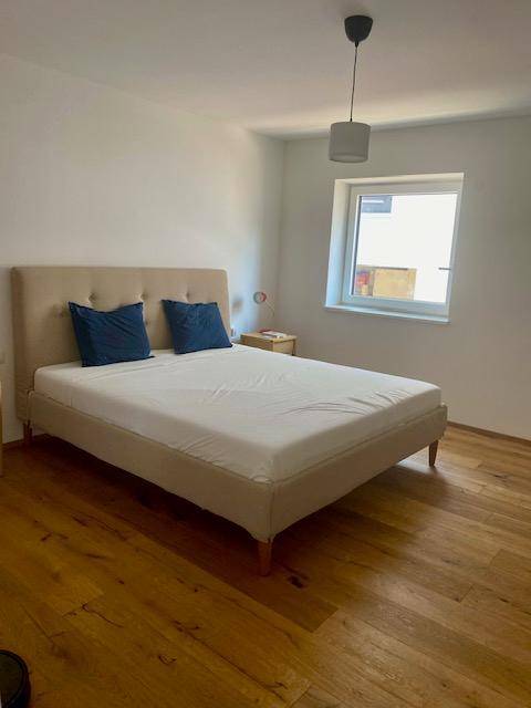 Schlafzimmer mit Doppelbett, Holzboden und einem Fenster für natürliches Licht.