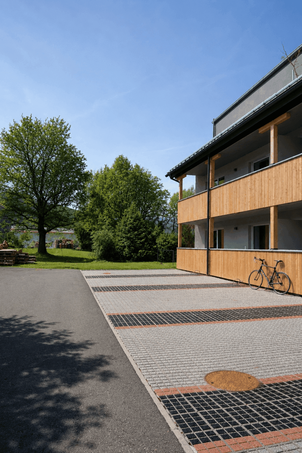 Außenansicht eines modernen Gebäudes mit Holzverkleidung, Balkonen und Parkplätzen.