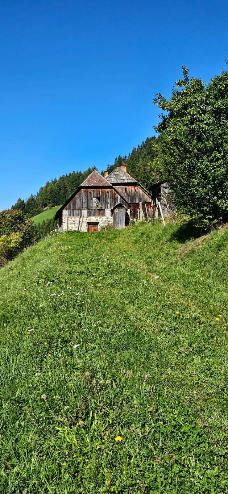 Rustikales Bauernhaus auf einem grünen Hügel mit weitem Blick über die Landschaft.
