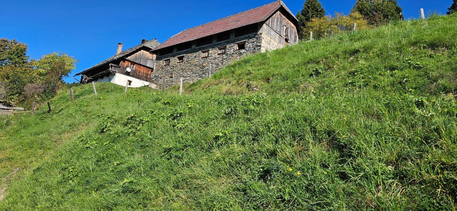 Ländliches Anwesen mit mehreren Gebäuden auf einem grünen Hügel mit weitem Blick.
