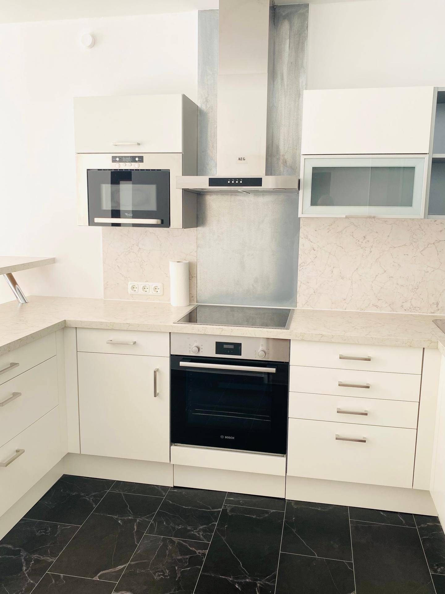 Detailansicht der modernen Küche mit integriertem Backofen, Induktionskochfeld und Mikrowelle.