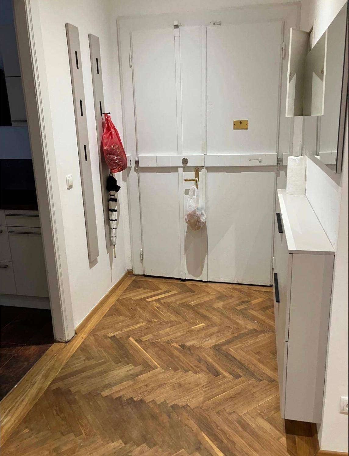 Flur mit Fischgrätparkettboden, Garderobe und Zugang zu weiteren Räumen.