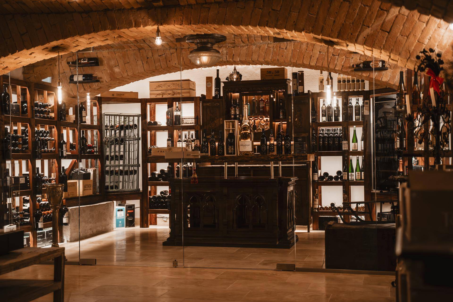Historischer Weinkeller mit Ziegelgewölbe, Holzregalen und einer beeindruckenden Weinsammlung.