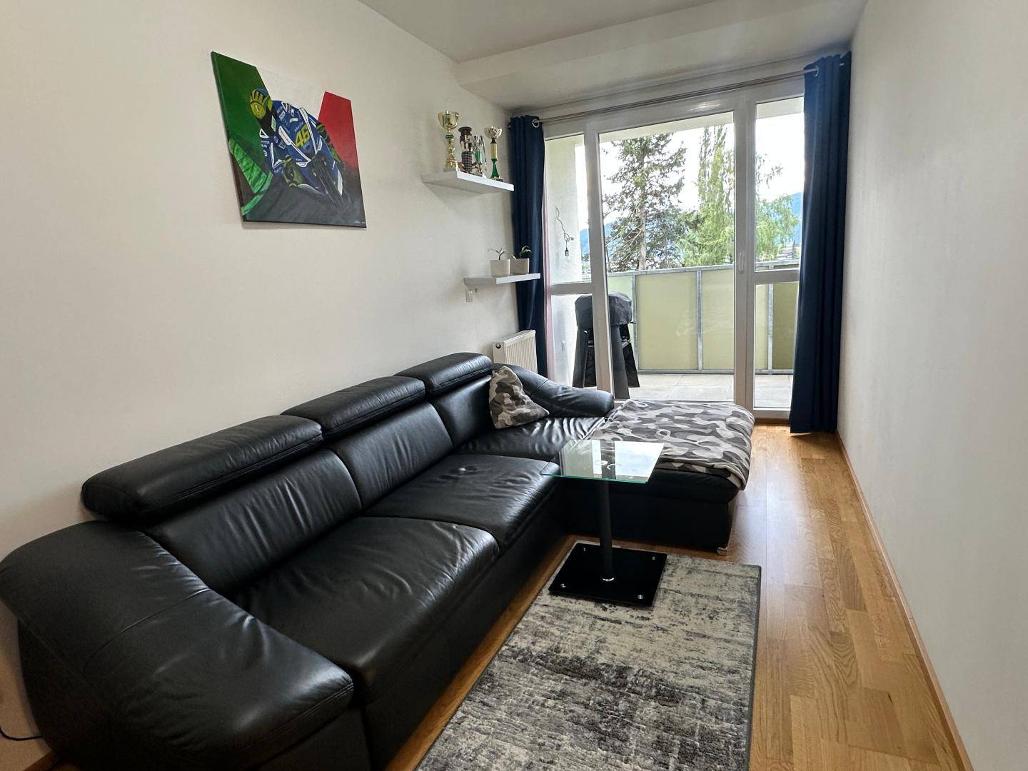 Helles Wohnzimmer mit großem Ledersofa, Holzboden und direktem Zugang zum Balkon.