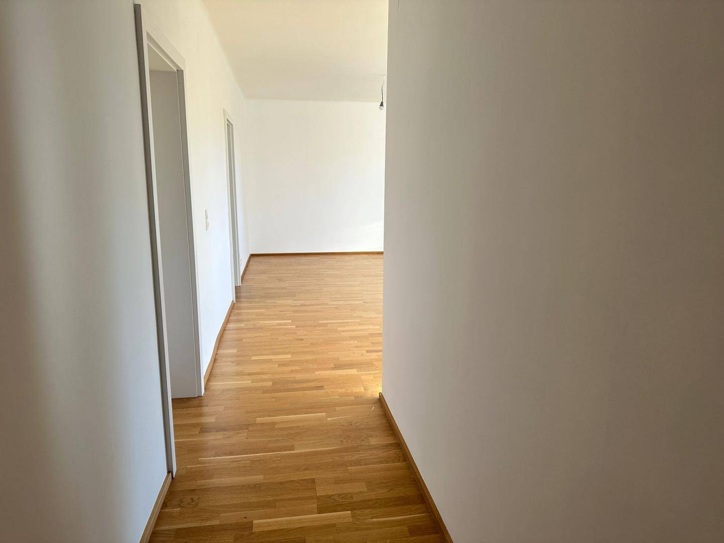 Langer Flur mit Parkettboden, der zu verschiedenen Zimmern führt und gut gepflegt ist.