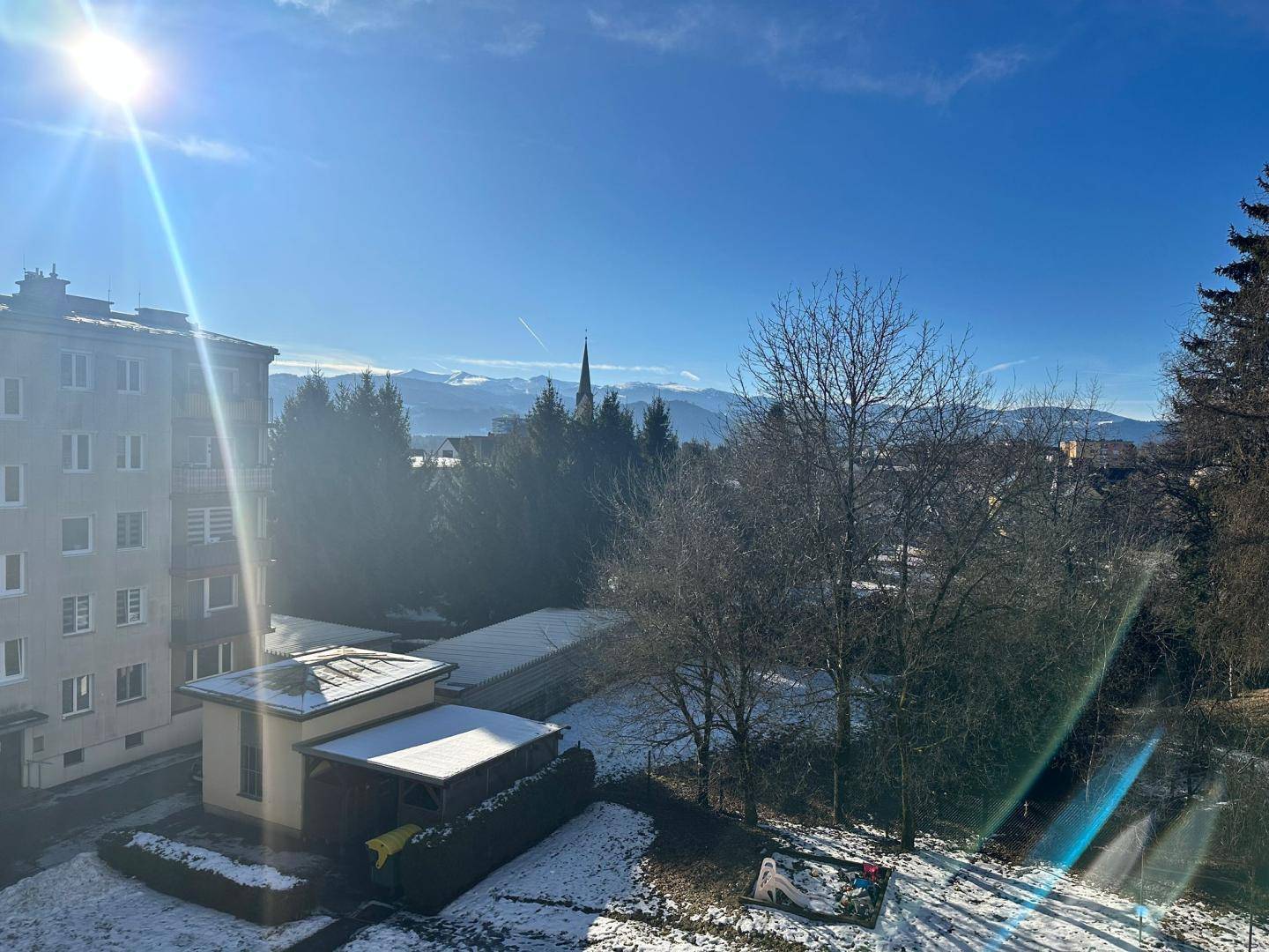 Panoramablick auf die verschneite Landschaft mit Bergen im Hintergrund und sonnigem Himmel.