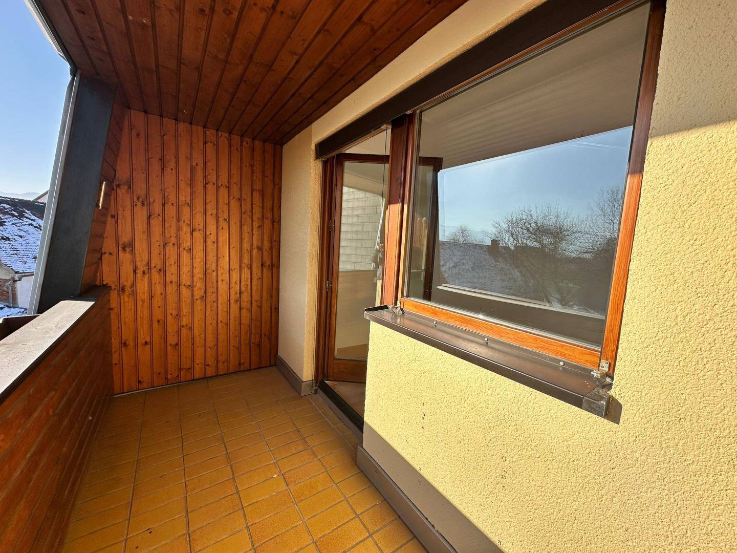 Gemütlicher Balkon mit Holzverkleidung und Fliesenboden, ideal für sonnige Stunden.