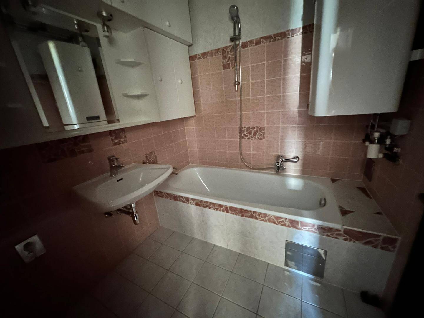Badezimmer mit Badewanne, Waschbecken und rosa Fliesen im klassischen Stil.