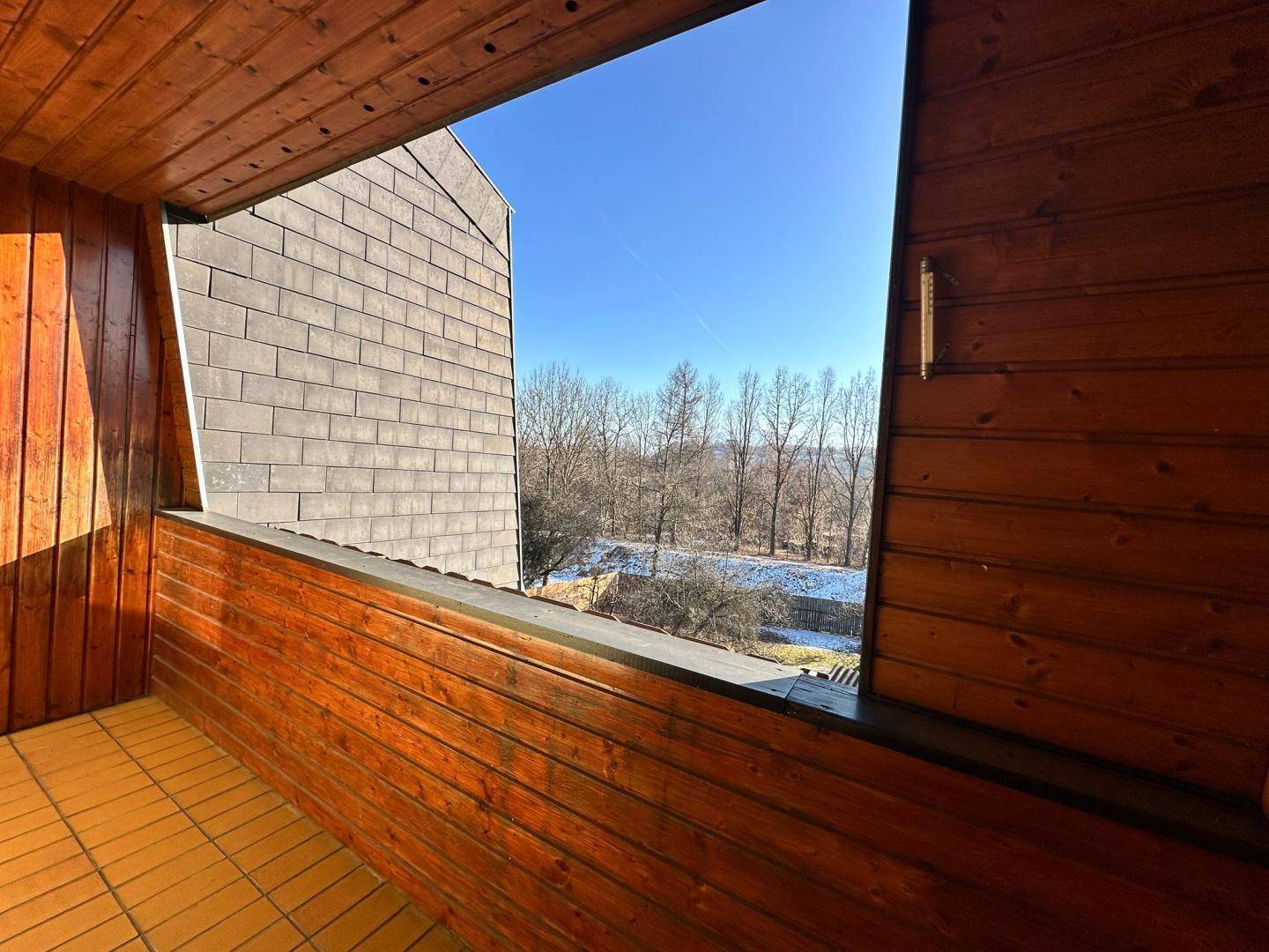 Balkon mit Holzverkleidung und Blick ins Grüne, ideal zum Entspannen im Freien.