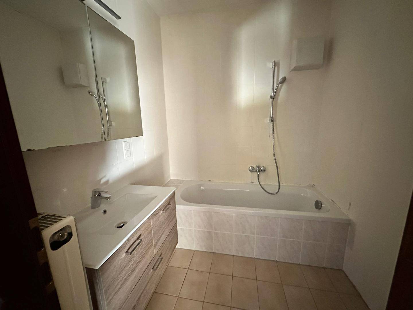 Badezimmer mit Badewanne, modernem Waschtisch und Spiegelschrank, in gutem Zustand.