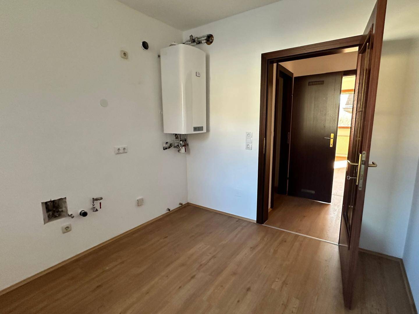 Hauswirtschaftsraum mit Warmwasserbereiter und Anschlüssen, bereit für die Installation.