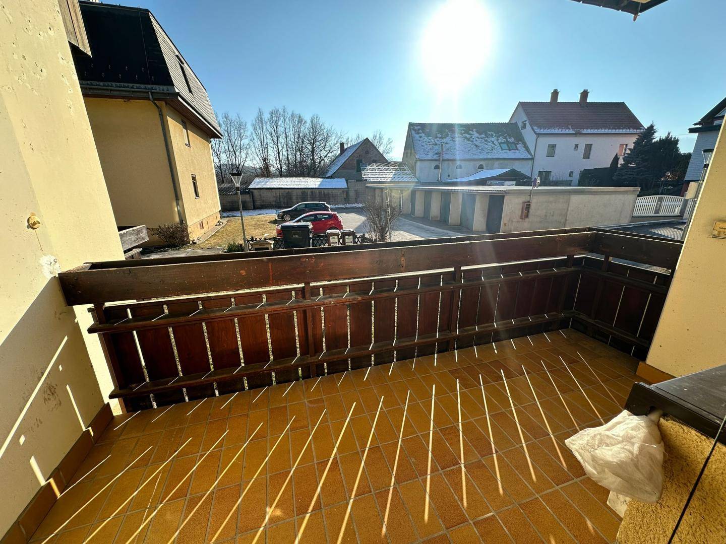 Sonniger Balkon mit Fliesenboden und Holzbalkonbrüstung, ideal zum Entspannen im Freien.
