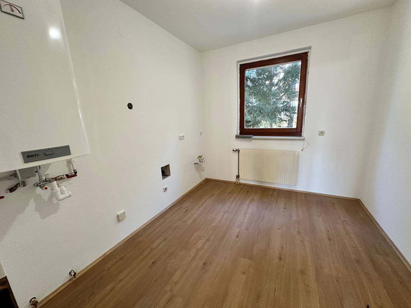 Hauswirtschaftsraum mit Heizungsanlage, Fenster und Anschlüssen für Waschmaschine oder Trockner.
