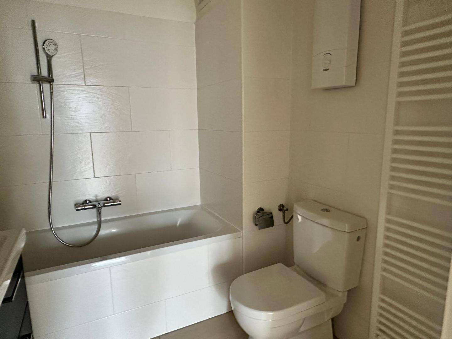 Funktionales Badezimmer mit Badewanne, Toilette und beheiztem Handtuchhalter.