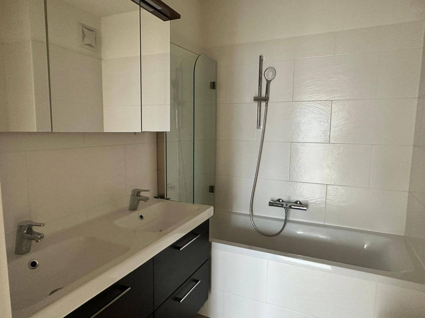 Modernes Badezimmer mit Badewanne, Duschfunktion und Waschtisch mit Spiegelschrank.