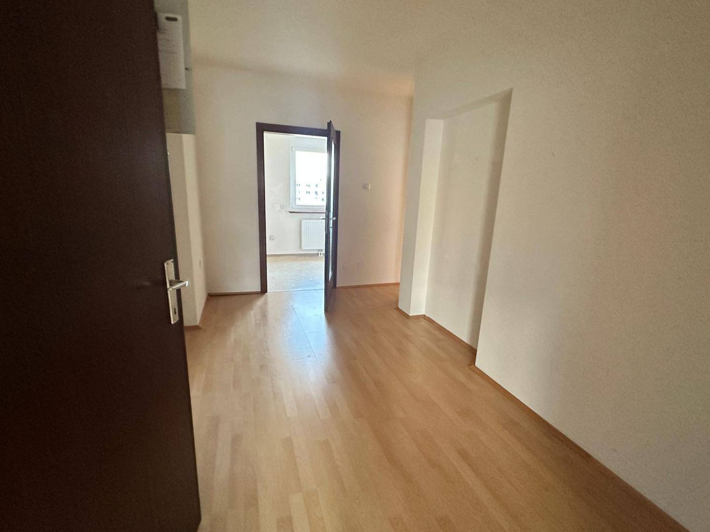 Heller Durchgangsbereich mit Laminatboden, der zu einem weiteren Zimmer der Wohnung führt.