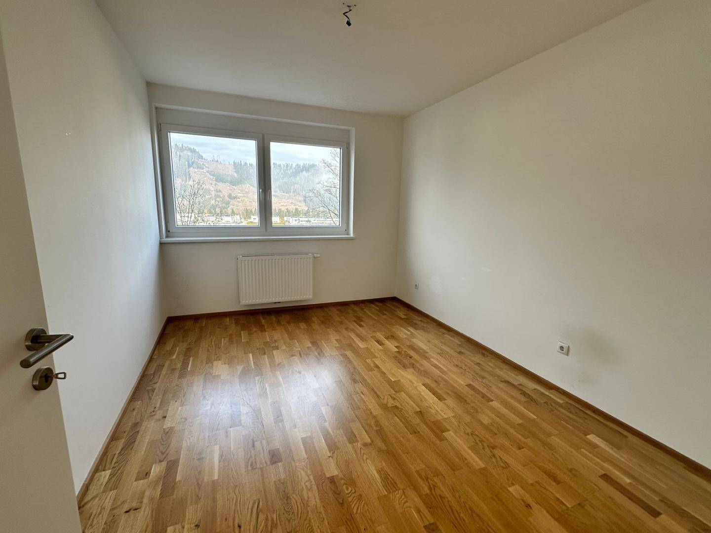 Helles Schlafzimmer mit Parkettboden und weitem Blick auf die umliegende Berglandschaft.