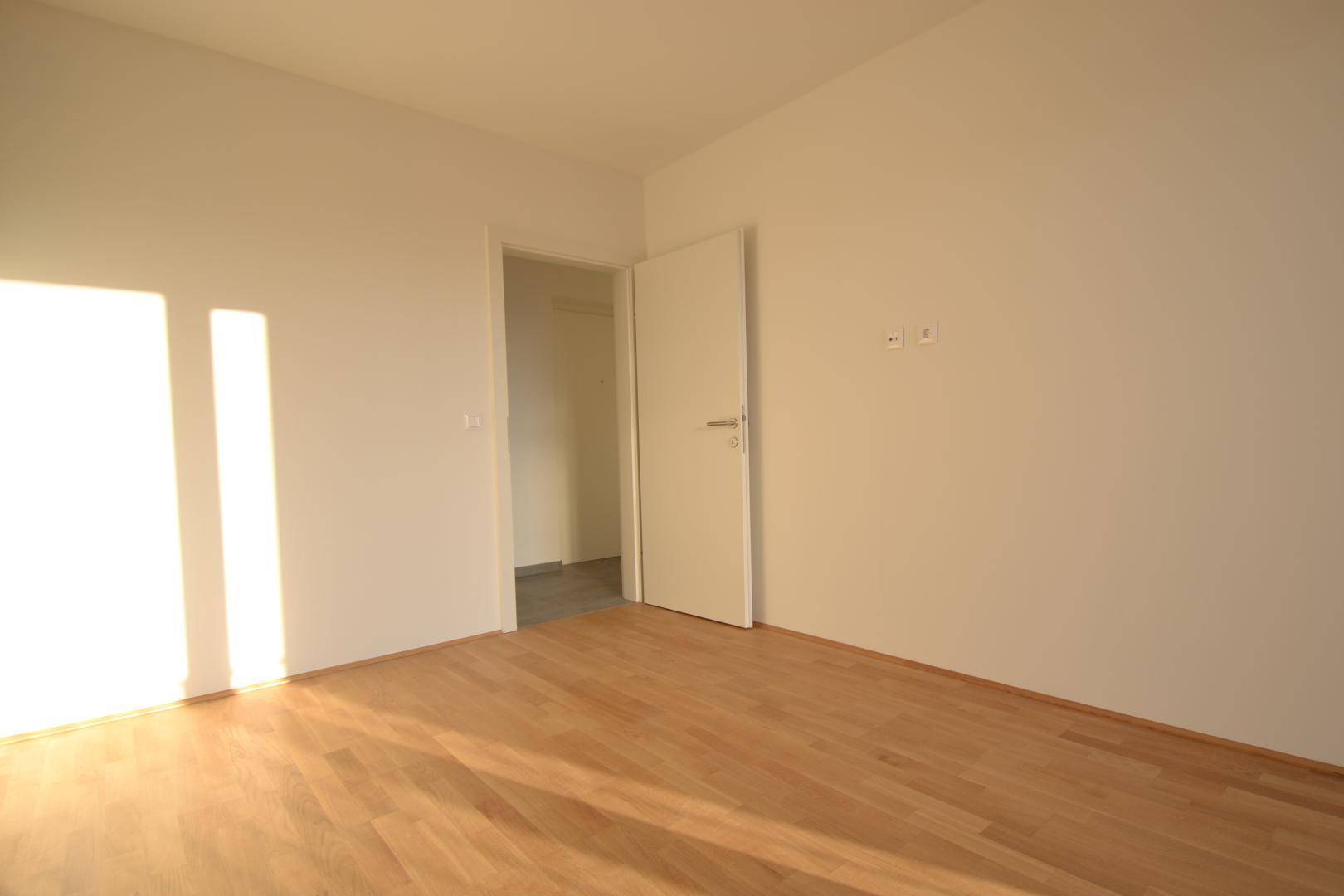 Geräumiges Zimmer mit hellem Parkettboden und weiß gestrichenen Wänden, bereit zur Einrichtung.