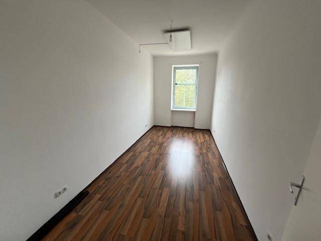 Schmaler, heller Raum mit Laminatboden und einem Fenster, ideal als Schlaf- oder Arbeitszimmer.