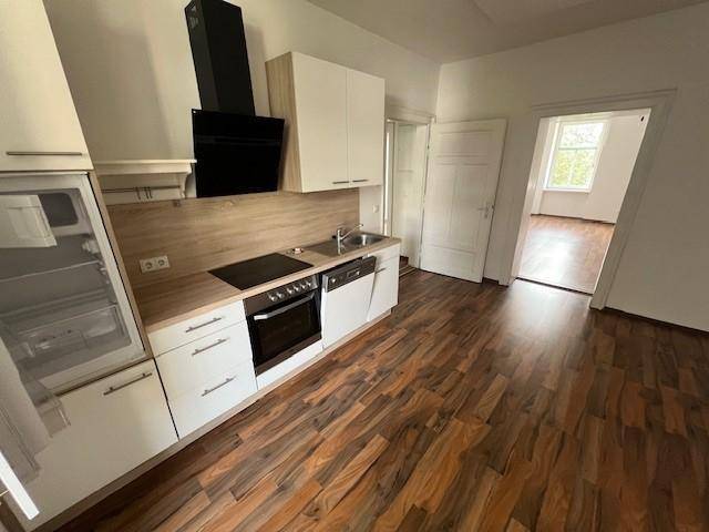 Funktionale Einbauküche mit modernen Geräten, Holzoptik-Arbeitsplatte und Laminatboden.