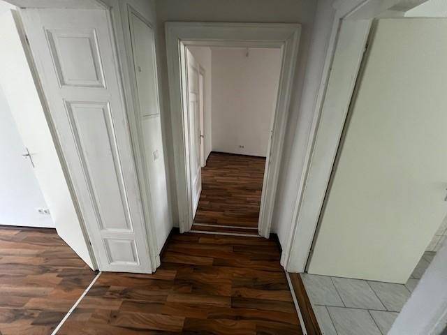 Heller Flur mit Laminatboden und weißen Türen, der verschiedene Räume miteinander verbindet.