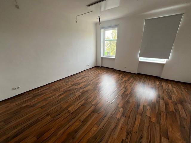 Geräumiges, lichtdurchflutetes Zimmer mit Laminatboden und zwei Fenstern, ideal für individuelle Gestaltung.
