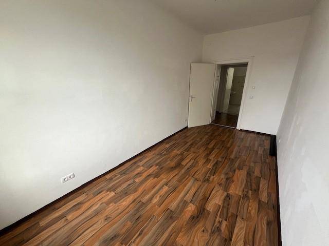 Geräumiges Zimmer mit Laminatboden und weißen Wänden, bietet vielseitige Nutzungsmöglichkeiten.