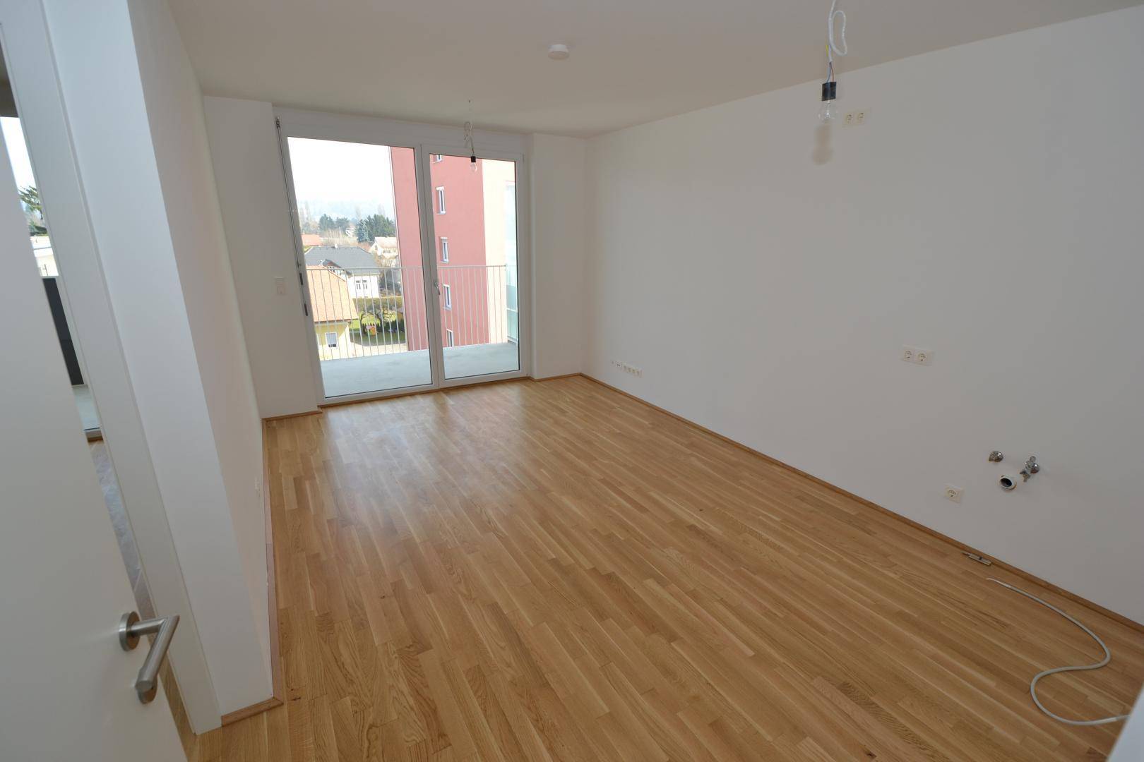 Geräumiges Zimmer mit Parkettboden und Balkonzugang, ideal als Wohn- oder Schlafzimmer.
