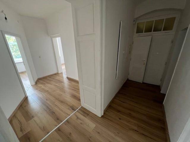 Heller Flur mit Laminatboden und mehreren Türen, der verschiedene Räume der Wohnung verbindet.