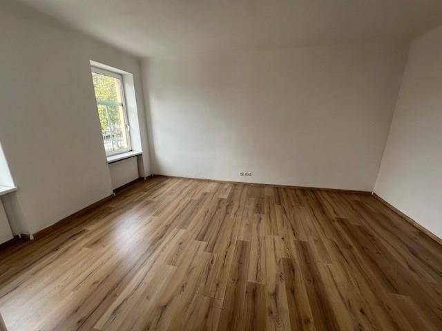 Geräumiges Zimmer mit Laminatboden und zwei Fenstern, die für viel Helligkeit sorgen.