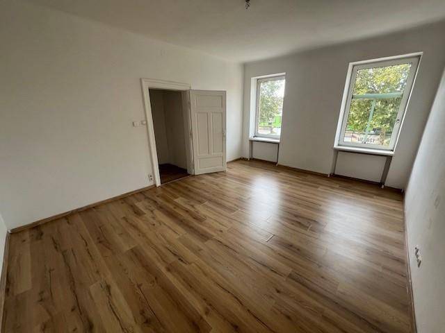 Helles Zimmer mit Laminatboden und zwei Fenstern, das viel Potenzial für verschiedene Nutzungen bietet.