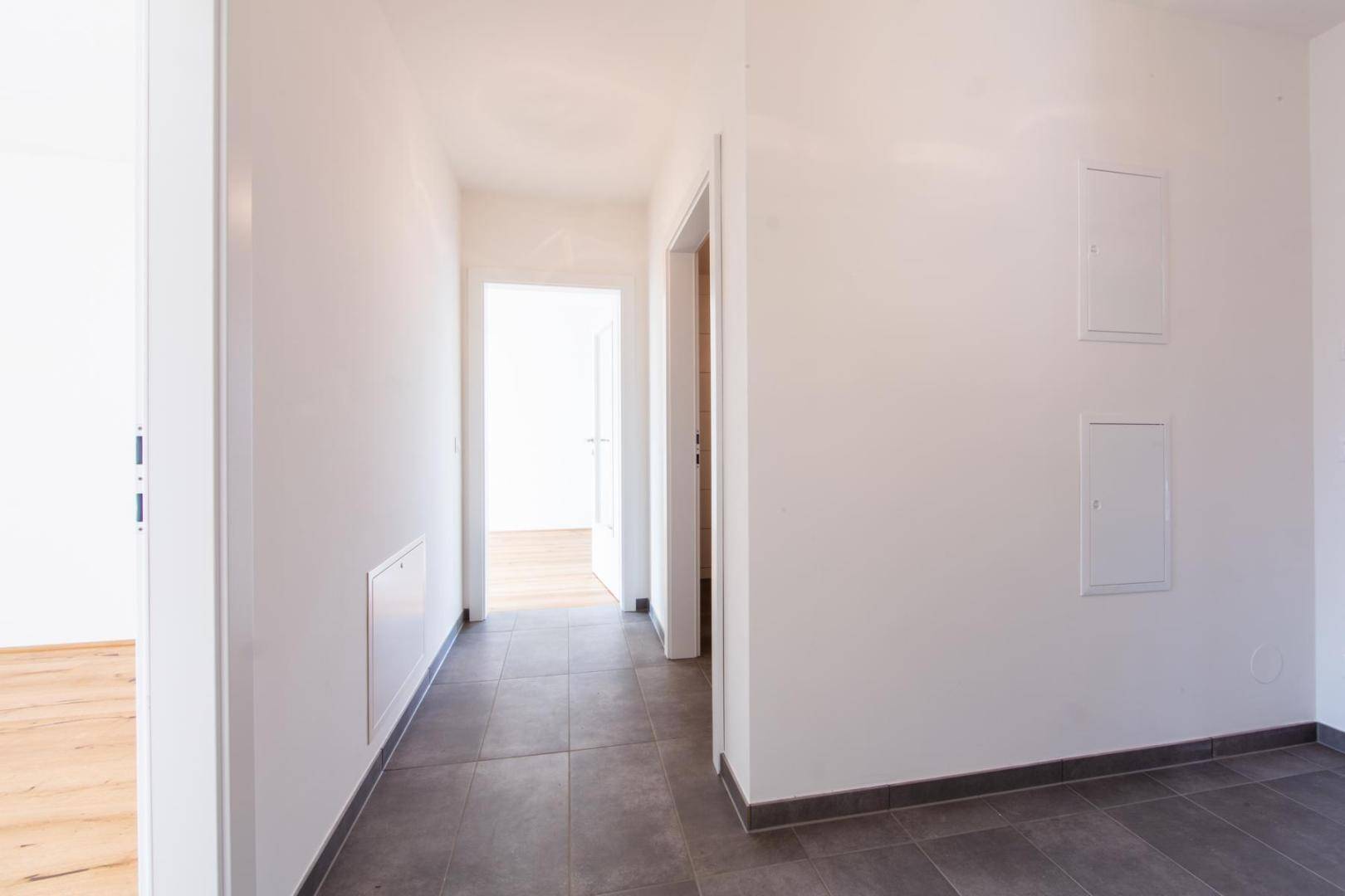 Langer, heller Flur mit Fliesenboden, der verschiedene Bereiche der Wohnung verbindet.
