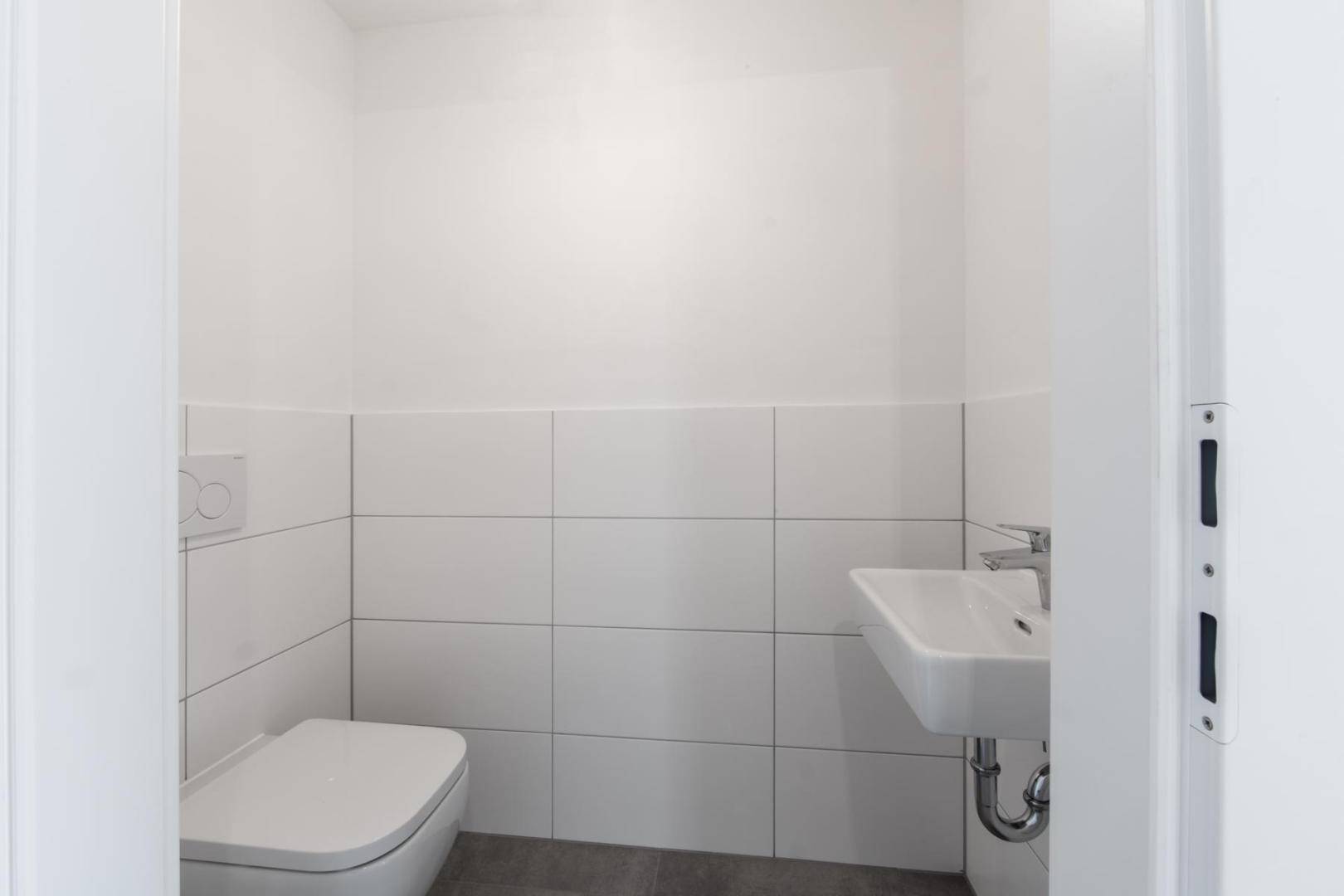 Kleines, modernes Gäste-WC mit wandhängender Toilette und einem einzelnen Waschbecken.