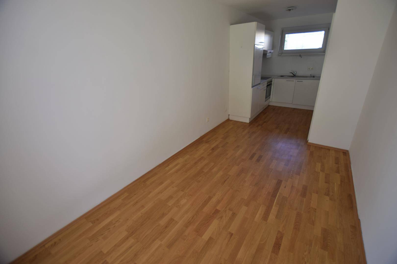 Heller Wohnbereich mit Parkettboden und offener Verbindung zur Küche, bietet vielseitige Gestaltungsmöglichkeiten.