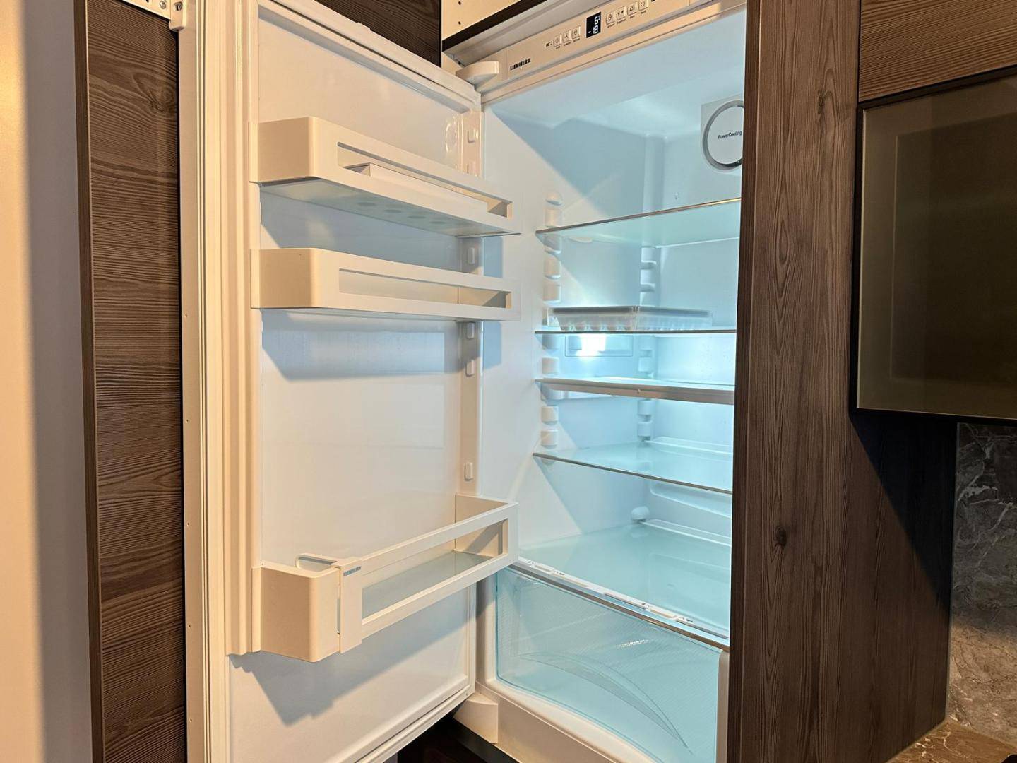 Offener Kühlschrank mit mehreren Ablagefächern und integriertem Licht in der Küche.